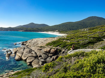 Scenic view of sea and mountains against clear blue sky