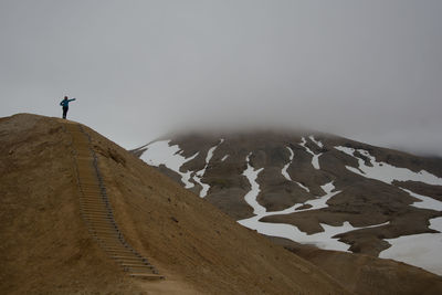 Rear view of man standing on mountain against clear sky