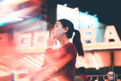 Low angle view of young woman in illuminated street at night