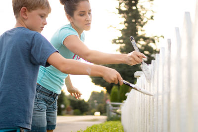 Mother and son painting fence