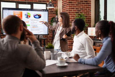 Businesswoman explaining chart to colleagues in meeting