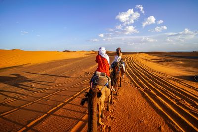 Rear view of people walking on desert