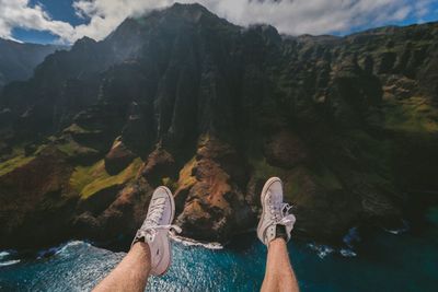 Low section of man on mountain against sky