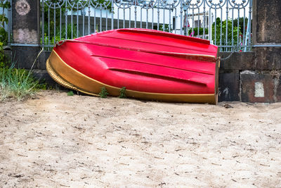 Red boat moored on land against wall