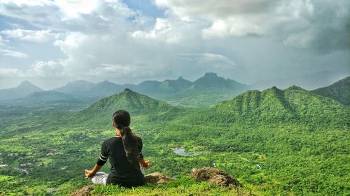 Rear view of woman looking at mountains against sky