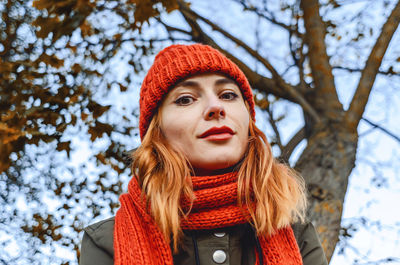 Bright cute young woman in orange warm knitted hat and scarf. autumn portrait close-up.