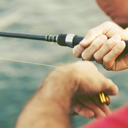 Cropped hands holding fishing rod