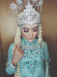 Beautiful woman in traditional clothing standing against wall