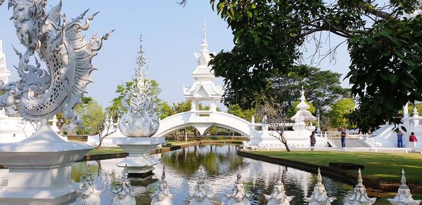 Statue by lake against sky