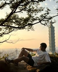 Side view of young man sitting on the rock watching the sunset 