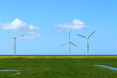 Wind turbines on field against sky