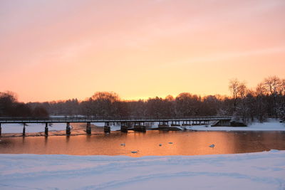 Scenic view of lake against orange sky during winter