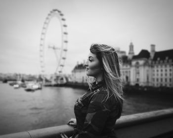 Profile view of woman standing on bridge against ferris wheel