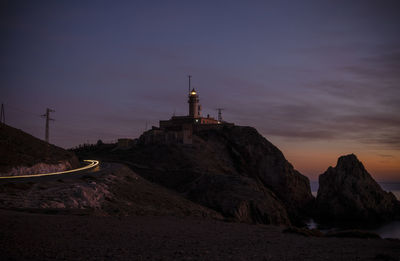 Lighthouse by sea against sky during sunset