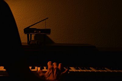 Person playing piano against wall