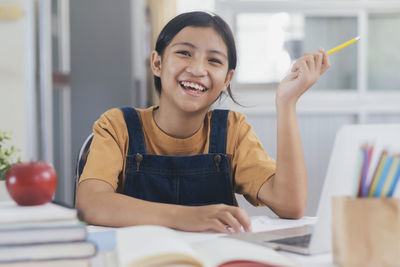 Happy asian girl learning online at home