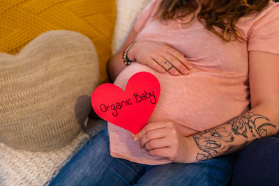 Midsection of woman holding heart shape