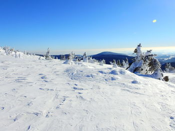 Scenic view of snow covered landscape against clear blue sky