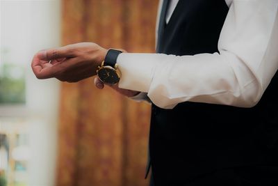 Midsection of businessman wearing wristwatch at home