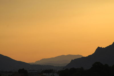 Scenic view of silhouette mountains against orange sky