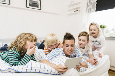 Family using digital tablet lying in bed at home