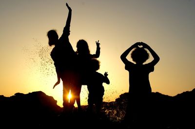 Silhouette children enjoying against clear sky during sunset