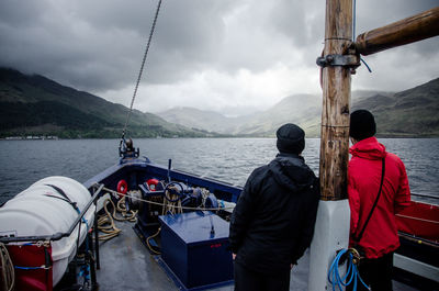 People standing on boat by mountain against sky