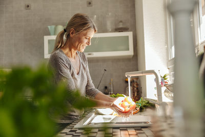Woman in kitchen washing tomatoes
