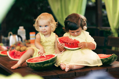 Girls eating watermelon on table