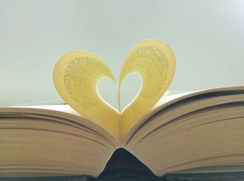 Close-up of heart shape made from pages against white background