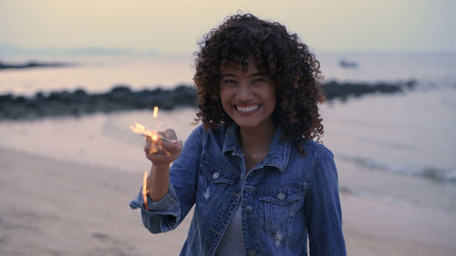 Portrait of smiling young woman standing on beach