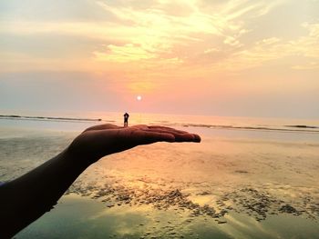 Hand pretending to hold couple on beach