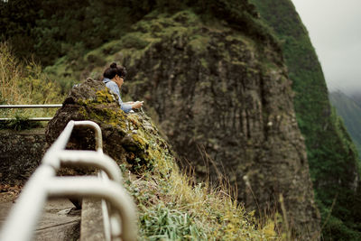 Side view of a woman sitting at rocky landscape