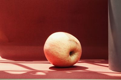 Close-up of apple on table against wall