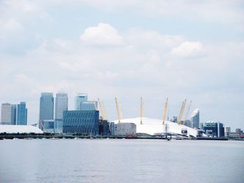 Modern cityscape by sea against sky