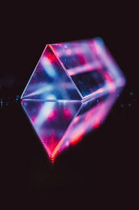 Close-up of illuminated lighting equipment on table against black background