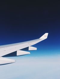 Low angle view of airplane wing against clear blue sky