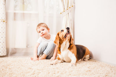 Boy looking at dog sitting on floor