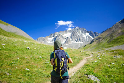 Rear view of man standing on mountain against sky