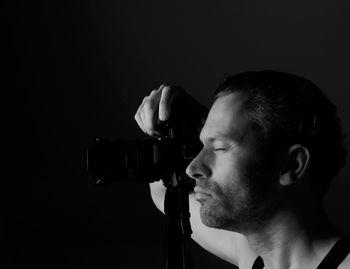 Close-up of man photographing against black background