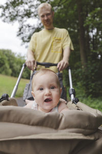Cute baby girl in stroller with father in background