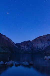 Scenic view of lake and mountains against sky at night