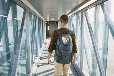 Rear view of man walking in passenger boarding bridge