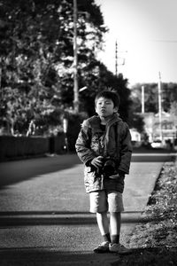 Boy with camera walking on footpath in city