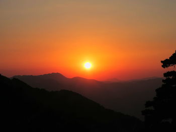 Silhouette mountains against orange sky during sunset