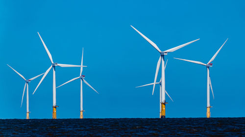 Wind turbines on land against clear blue sky