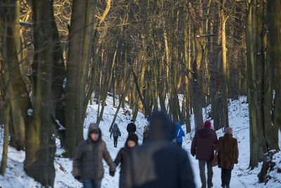 People walking on snow covered trees in forest