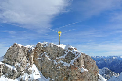 Pole on frozen rock against sky