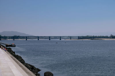 Bridge over sea against clear blue sky