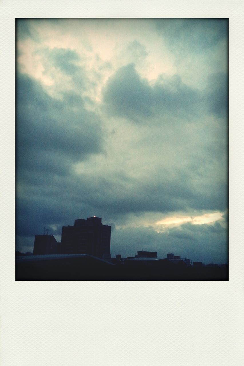 building exterior, architecture, built structure, sky, transfer print, cloud - sky, cloudy, auto post production filter, city, low angle view, silhouette, building, cloud, weather, overcast, dusk, outdoors, residential building, tower, residential structure